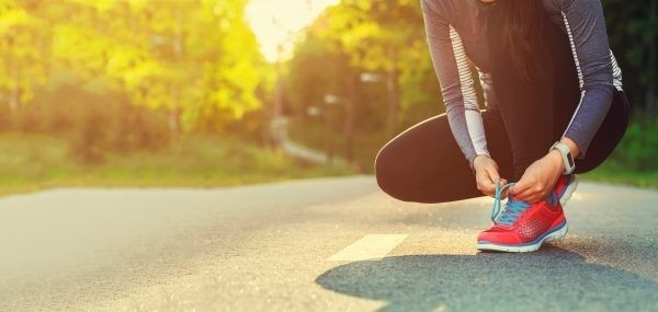 Läuferin bindet sich auf einer Straße die roten Laufschuhe