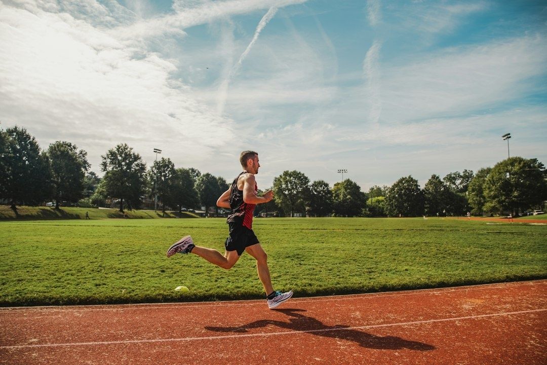 Läufer beim dynamischen Aufwärmen auf einer Sportplatzbahn